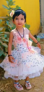 Young child in a floral dress with yellow background.