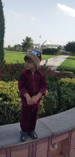 Child wearing maroon outfit in a garden setting.