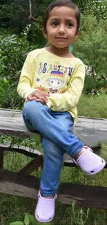 Child sitting on a bench in a lush green outdoor setting.