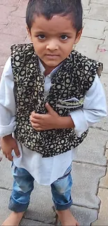 Young child in a stylish vest on a stone path.