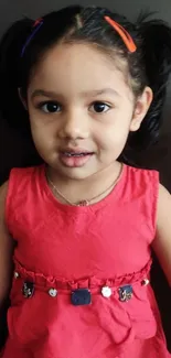 Adorable young child in red dress smiling.