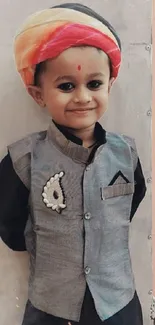 Smiling child in traditional attire with a colorful turban.