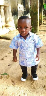 Adorable child in blue attire standing outside.