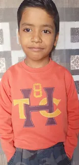 Young boy in a coral sweater with a charming smile.