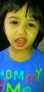 Portrait of child in blue shirt with vibrant colors.