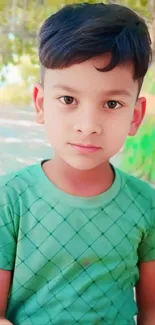 Young boy in a green shirt standing outdoors.