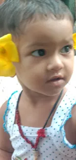 Child wearing yellow flowers with a charming smile.