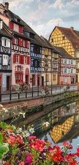 Vibrant village houses reflecting in canal with flowers.