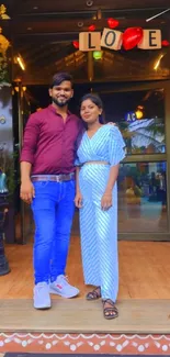 Couple posing at a café entrance with love decorations.