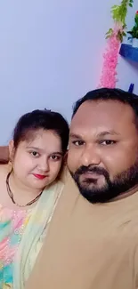 A happy couple poses in their home with colorful decor.