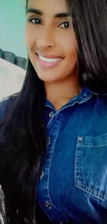 Woman in denim shirt smiling against a white and green background.