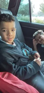 Two kids enjoying a car ride with smiles.