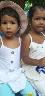 Two young girls in white dresses enjoying a day outdoors under lush greenery.