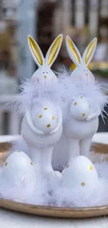 White bunnies with feathers on a tray and decorative eggs.