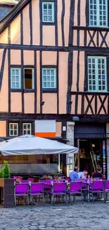 Charming European street with cafes and historic timbered buildings.