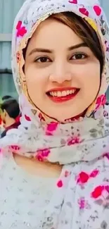 A woman smiling in white floral scarf.