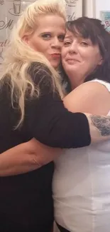 Two women share a warm embrace in a friendly and joyful moment.