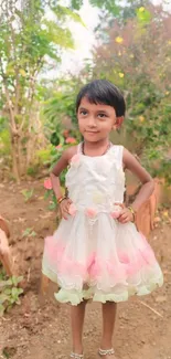 Child in white dress standing in a vibrant garden.