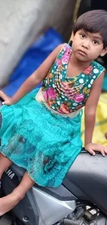 Young child in colorful dress sitting on a motorcycle.