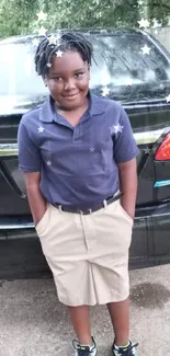 Charming child posing in front of black car with star effects.