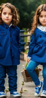 Two kids in stylish blue coats, standing outdoors smiling.