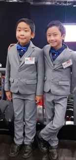 Two children in matching grey suits at an event.