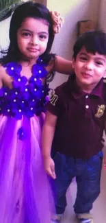 Two cute kids, one in purple dress, smiling happily.