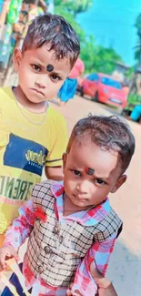 Two children posing on a vibrant street.