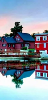 Vibrant lakeside village reflected on tranquil water under a colorful sky.