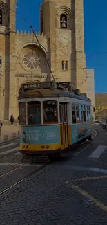 Lisbon tram passing Se Cathedral under clear blue skies.