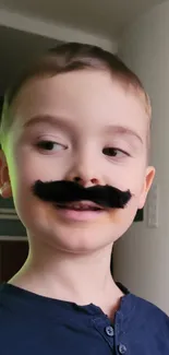 Adorable young boy with a fake moustache smiling in a cozy living room.