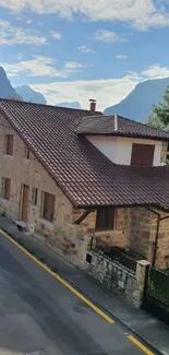 Charming stone house amidst mountain scenery with clear skies.