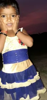 Adorable child in colorful dress with night sky backdrop.