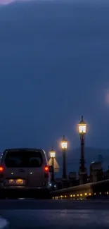 Night street with glowing lamps and car under dark blue sky.