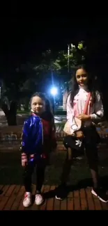 Nighttime portrait of two children on a street with vibrant jackets.