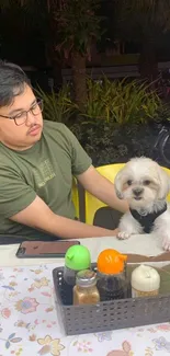 Man and dog enjoying a cafe setting with greenery.