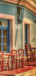 Vibrant outdoor café with red chairs and rustic blue wall.