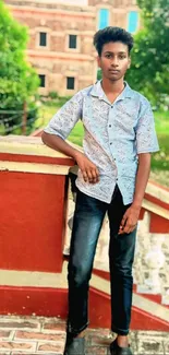 Young person in a scenic outdoor setting, leaning on a red railing.