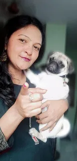 Woman holding a cute pug with a green background.