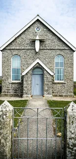Vintage stone church with blue sky and fields, serene country scene.