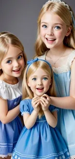 Three smiling children in matching blue dresses, creating a charming and joyful scene.