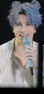 Singer with blue hair smiling on stage in elegant attire.