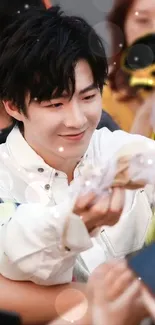 Person in white shirt smiling at crowd, engaging warmly.