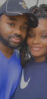 Couple smiling in casual outdoor portrait with blue and black attire.