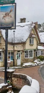 Charming snowy village with thatched cottages and historic sign in winter.