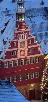 Snowy village with red building and festive lights by night.