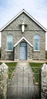 Charming stone church with blue sky and serene landscape in the background.