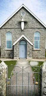 Historic stone church with gate and sky.