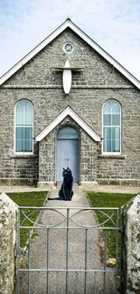 Charming stone church with cat statue and gray brick facade.