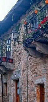 Charming stone house with vibrant flowers on balcony.